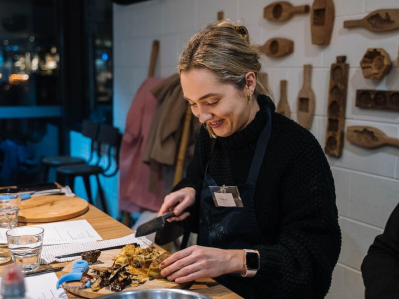 woman smiling while chopping ingredients on a wooden board
